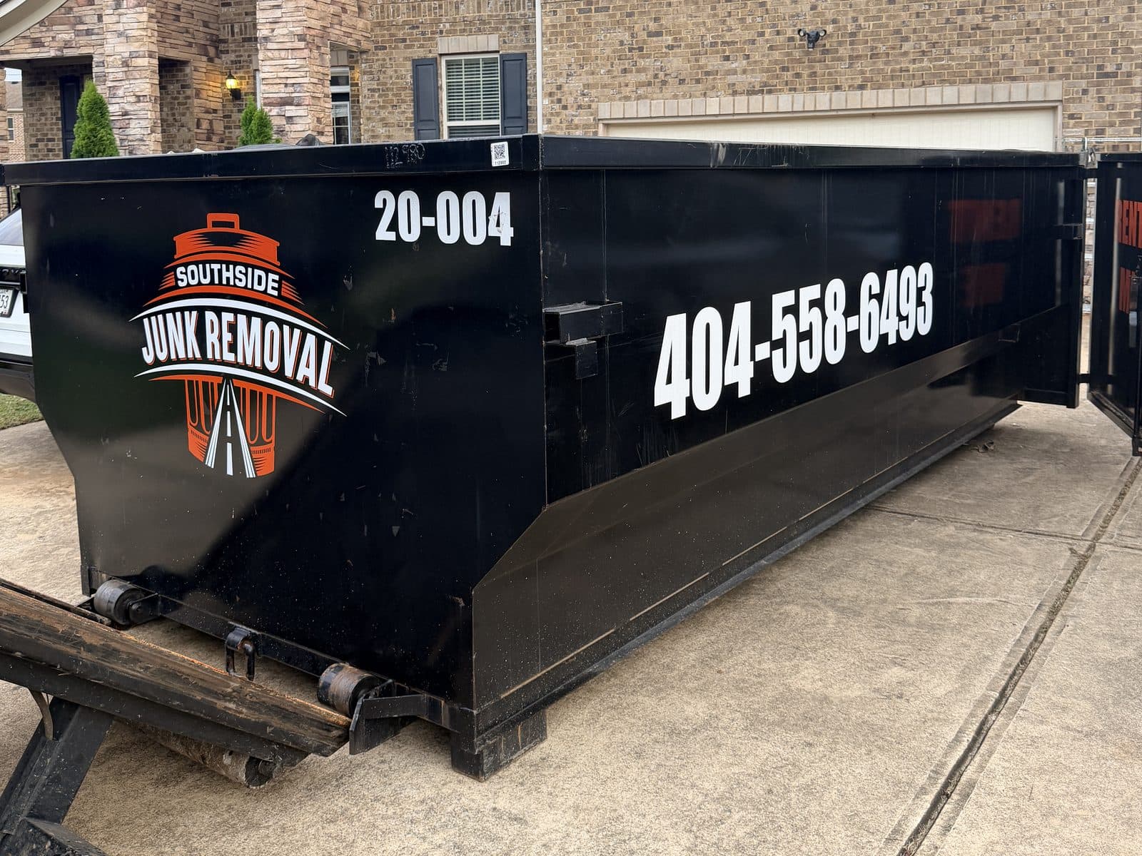 Black 20-yard Southside dumpster (unit 20-004) in the driveway of a brick home
