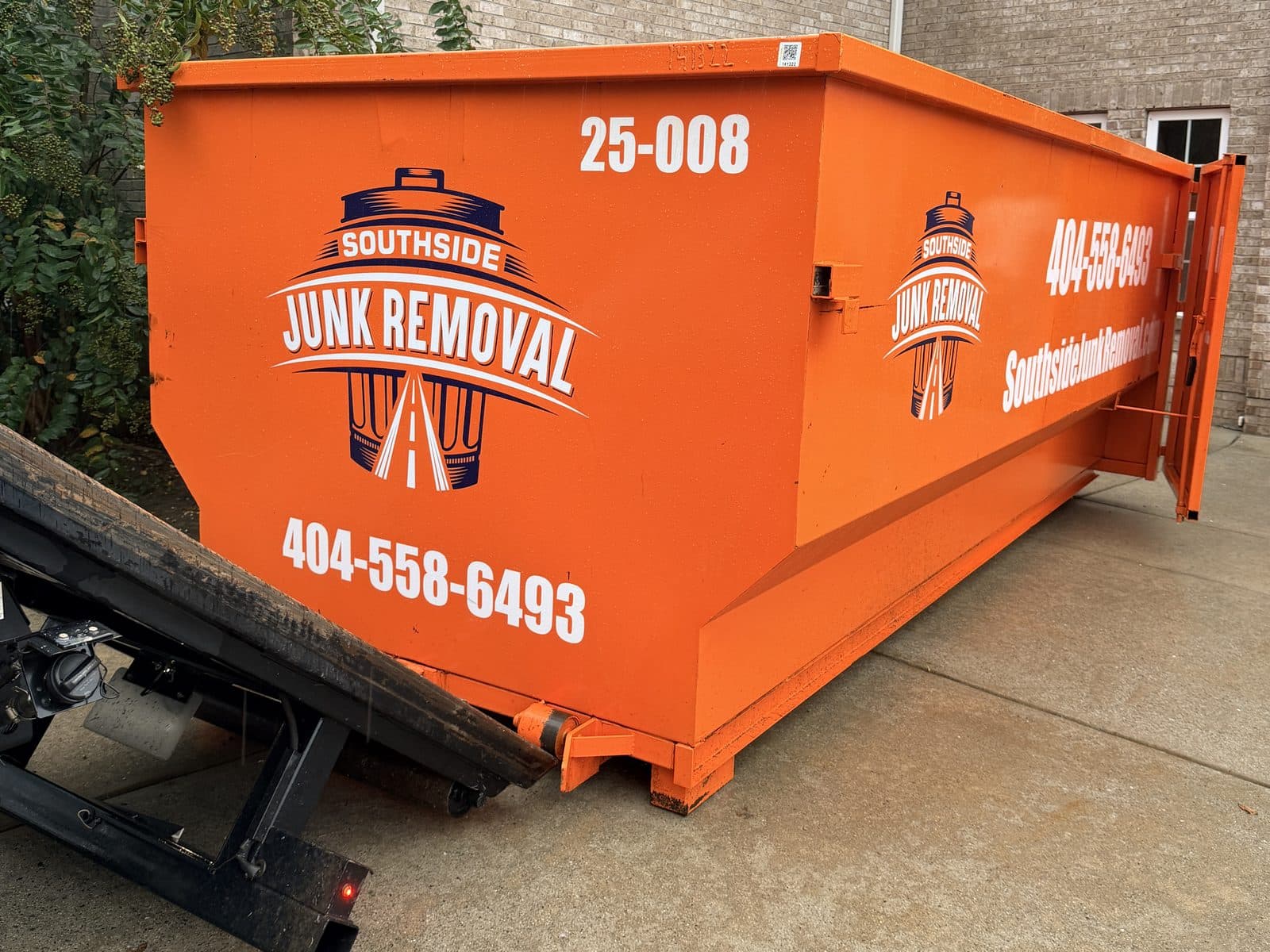 Orange 25-yard Southside dumpster (unit 25-008) in the driveway of a brick home