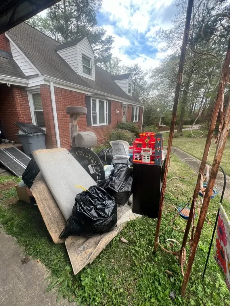 Old furniture, mattress and bags piled on a front lawn