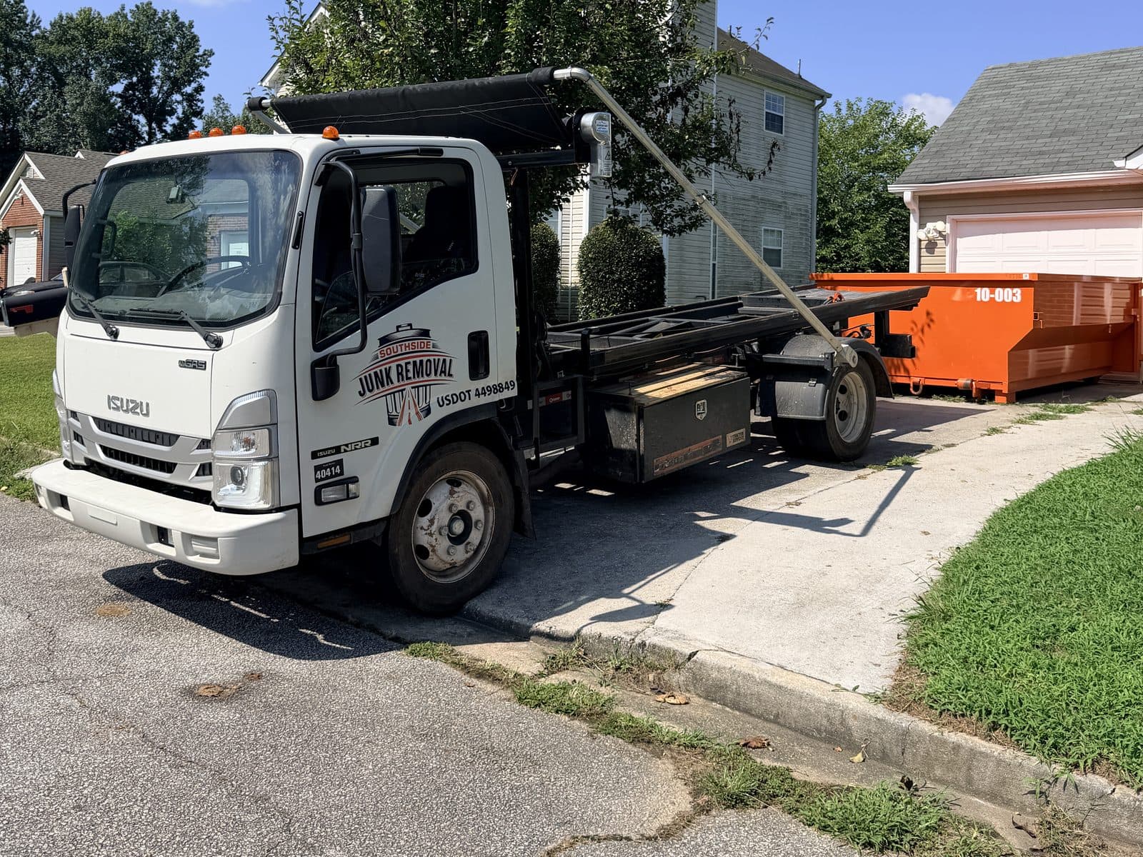 Southside roll-off truck in front of an orange 10-yard dumpster (unit 10-003) in a driveway