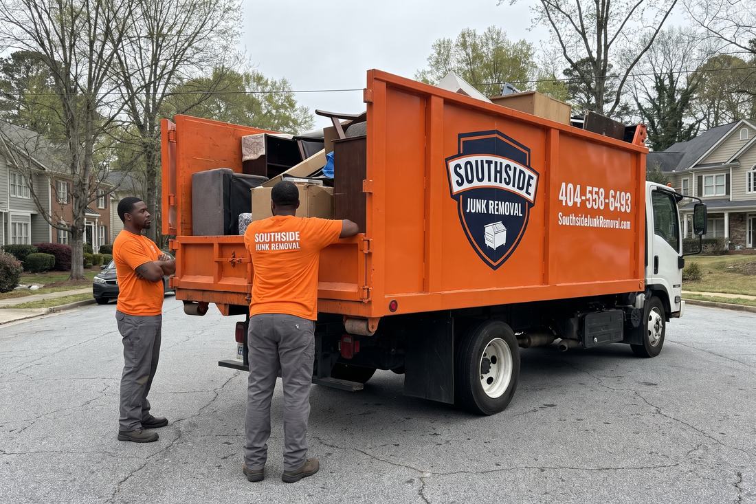 Two Southside Junk Removal crew members standing beside the loaded orange dump truck at the end of a completed Atlanta junk removal job