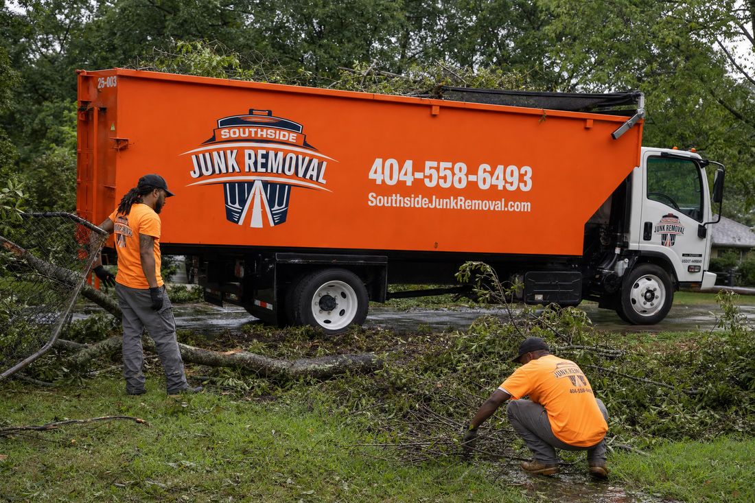 Southside Junk Removal crew clearing fallen storm branches and yard debris beside the dump truck in metro Atlanta