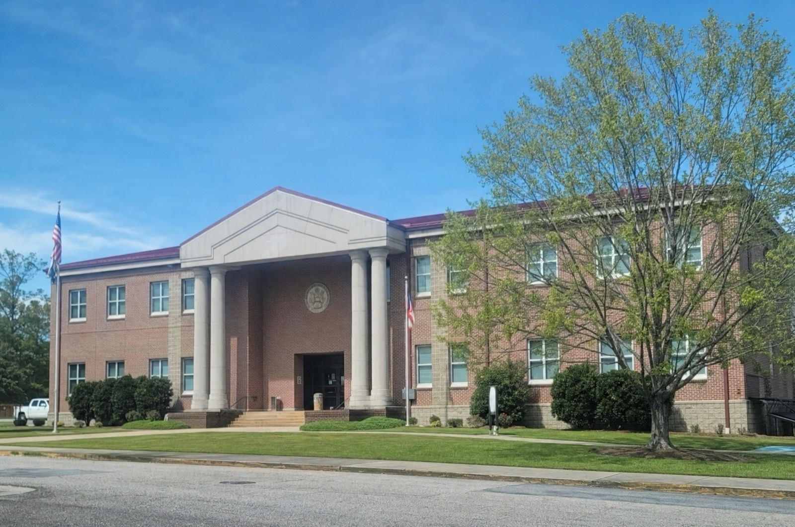 Brick civic building with a columned entrance and flags, Hampton, GA