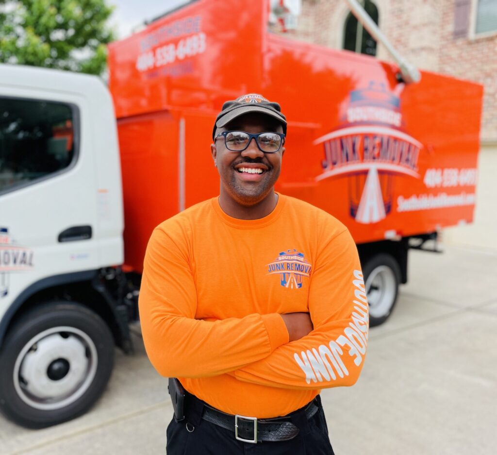 Smiling junk removal professional standing next to the truck