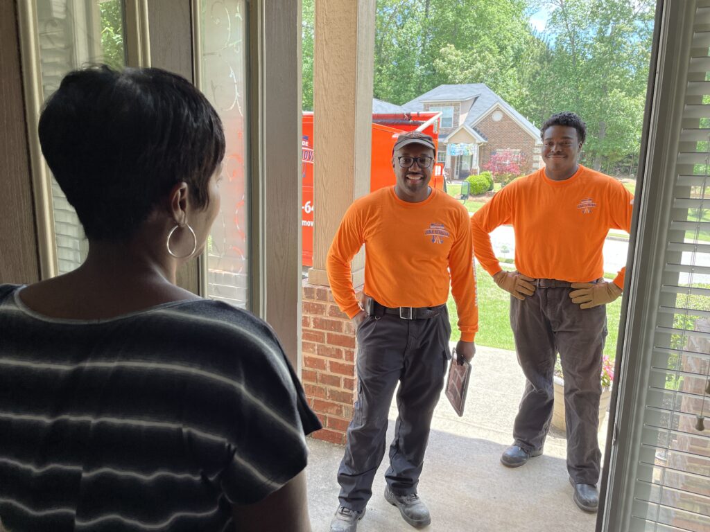Smiling junk removal professionals greeting a customer at the door
